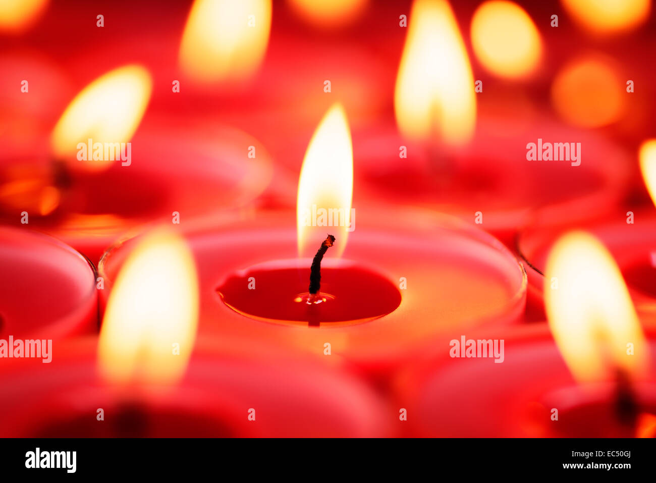 Backgrounds and textures: close-up shot of burning red candles, selective focus, holiday or celebration background Stock Photo