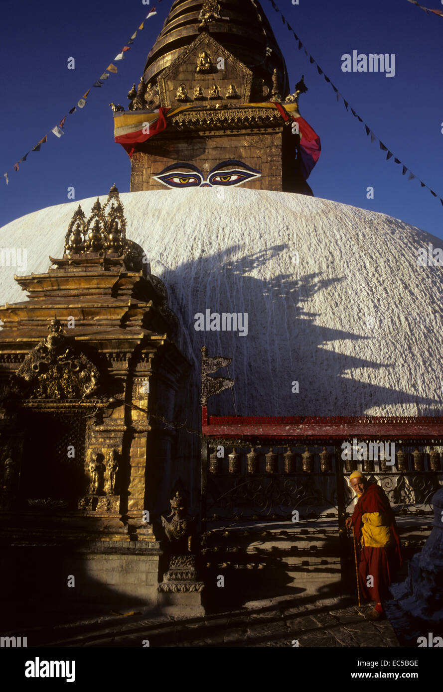 A Buddhist monk turns prayer wheels around the stupa of Swayambhunath ...