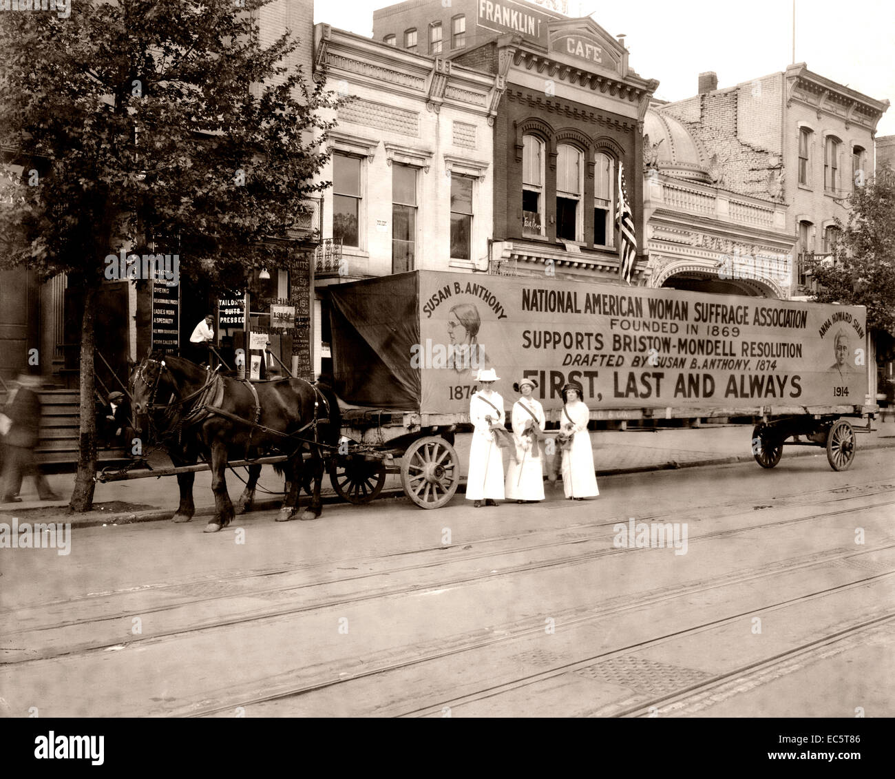 Three women standing in the street in front of horse-drawn wagon with sign, National American Woman Suffrage Association founded in 1869 supports Bristow-Mondell Resolution drafted by Susan B. Anthony, 1874, 'First, Last and Always.' Circa 1917. Stock Photo