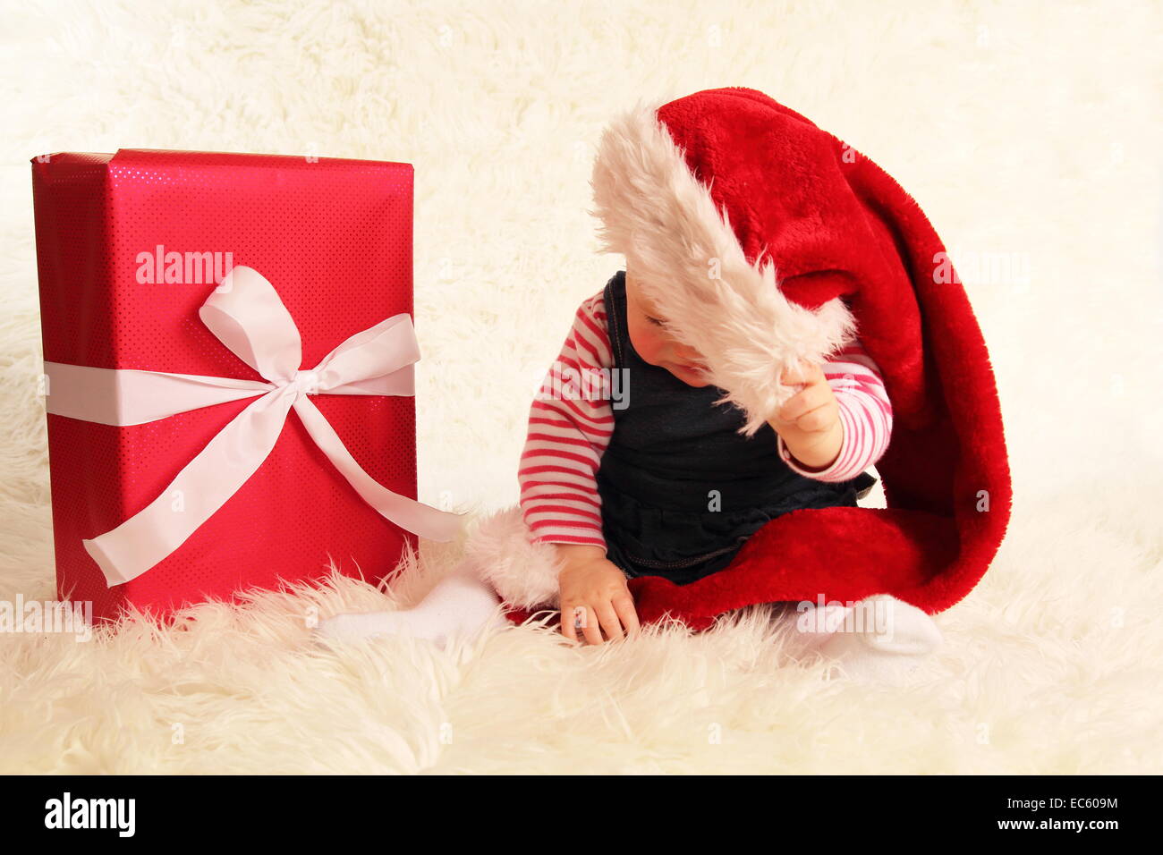 A Baby beyond a santa claus hat and gift Stock Photo