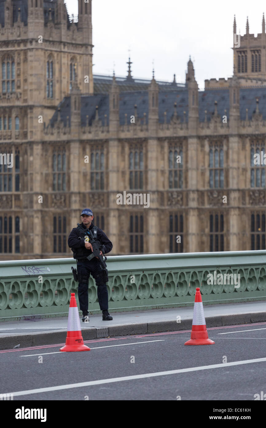 An armed officer of the Metropolitan Police in London stands guard on Westminster Bridge, outside the House of Parliament Stock Photo
