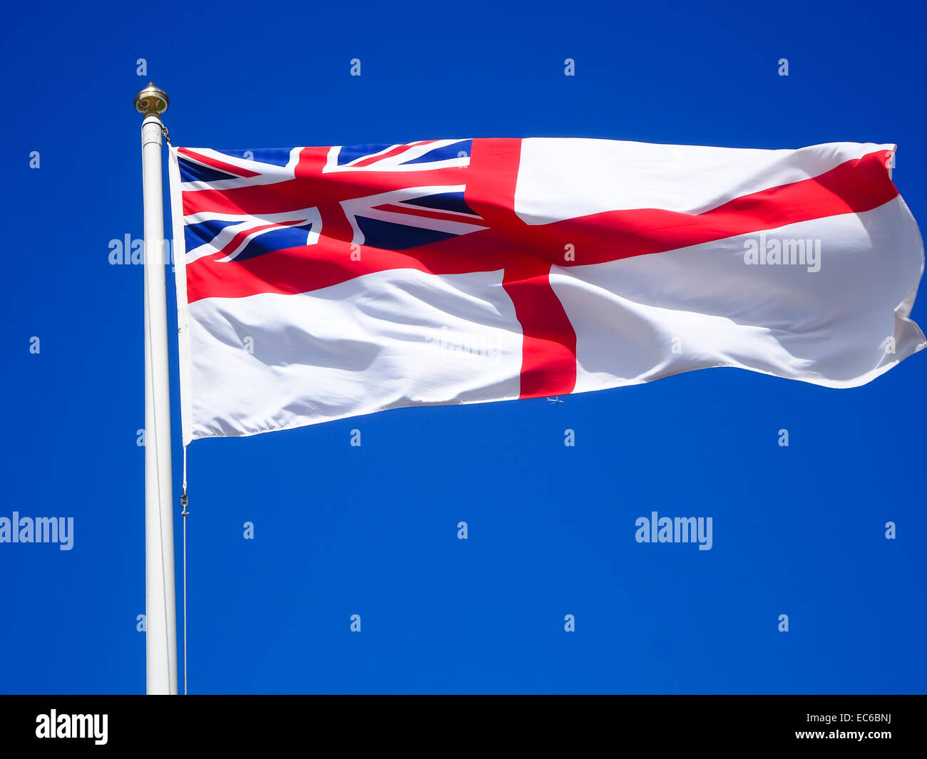 A White ensign flying at the top of a flag pole against a blue sky Stock Photo