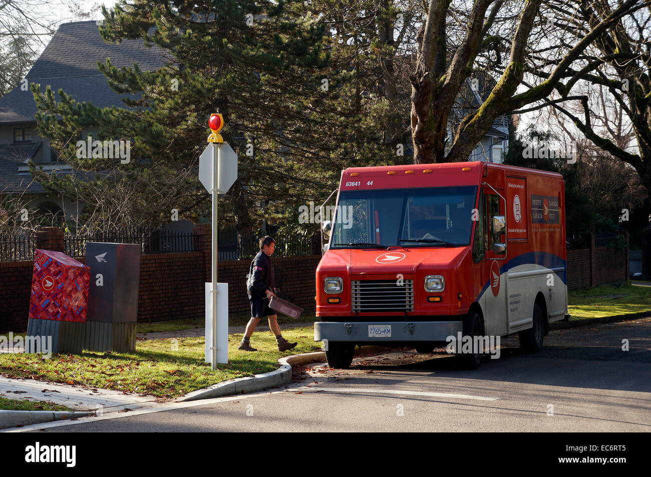 Mailman and Canada Post mail truck on a residential street in Vancouver, BC, Canada Stock Photo