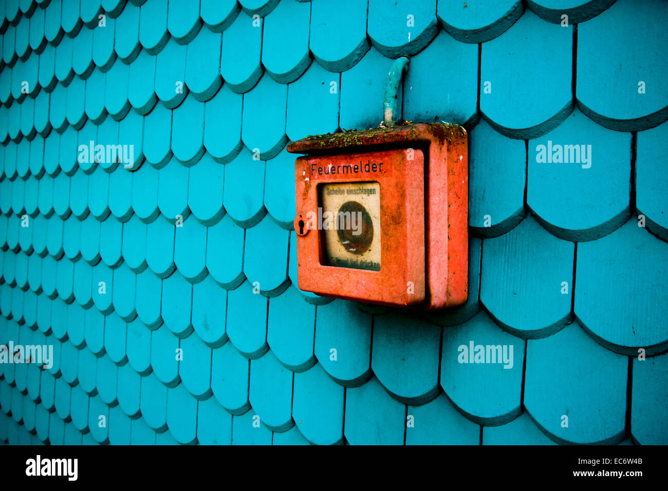 Emergency red fire alarm on blue house wall oblique view with depth Stock Photo
