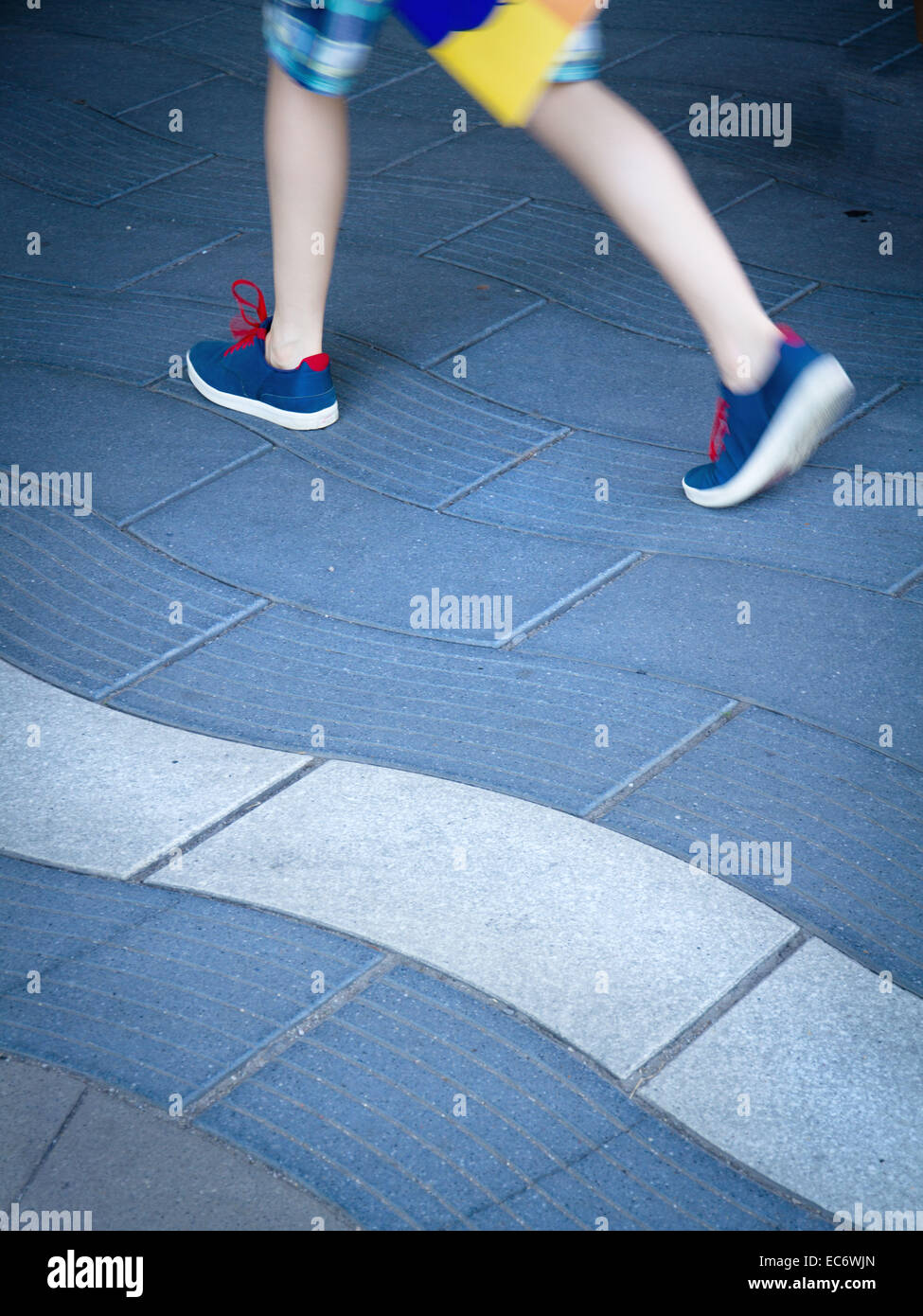 Pedestrians on undulating pavement slabs, optical illusion Stock Photo