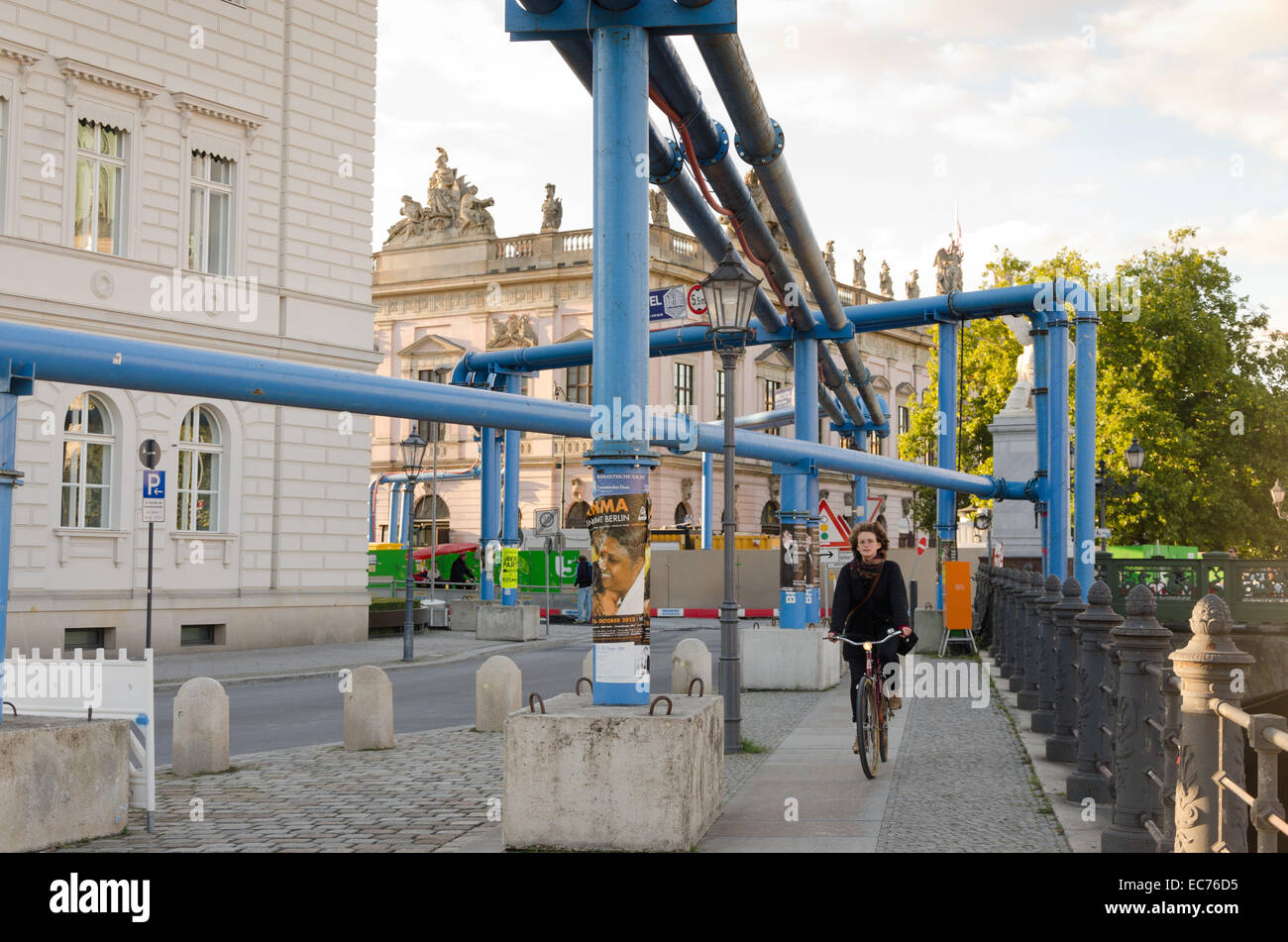 BERLIN, GERMANY - SEPTEMBER 29: A young bicyclist on a sidewalk with painted blue pipes for drainage construction of a subway li Stock Photo