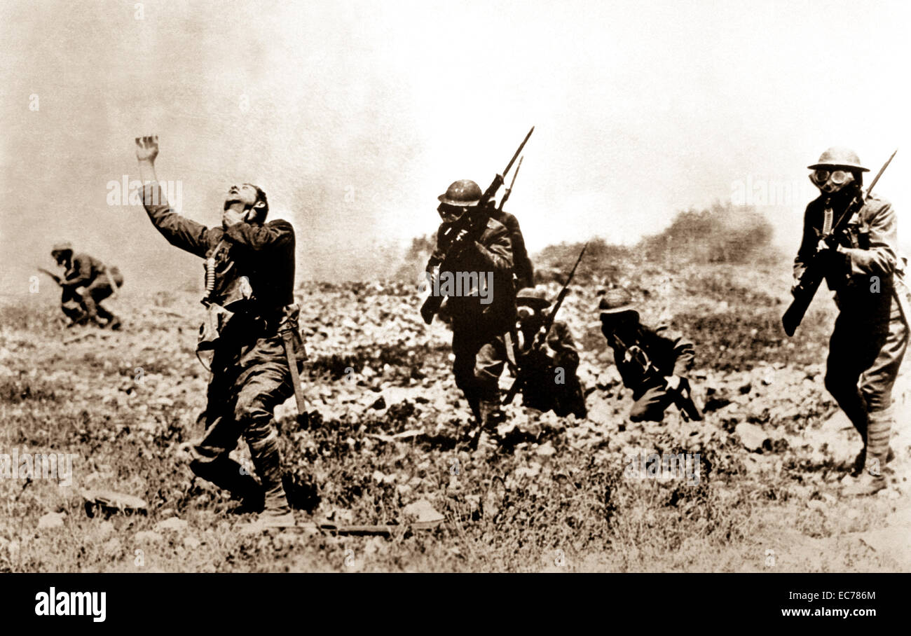 A  posed photograph of troops charging forward on a battlefield in France, near front line trenches, to illustrate effects of phosgene gas.  1918. Stock Photo