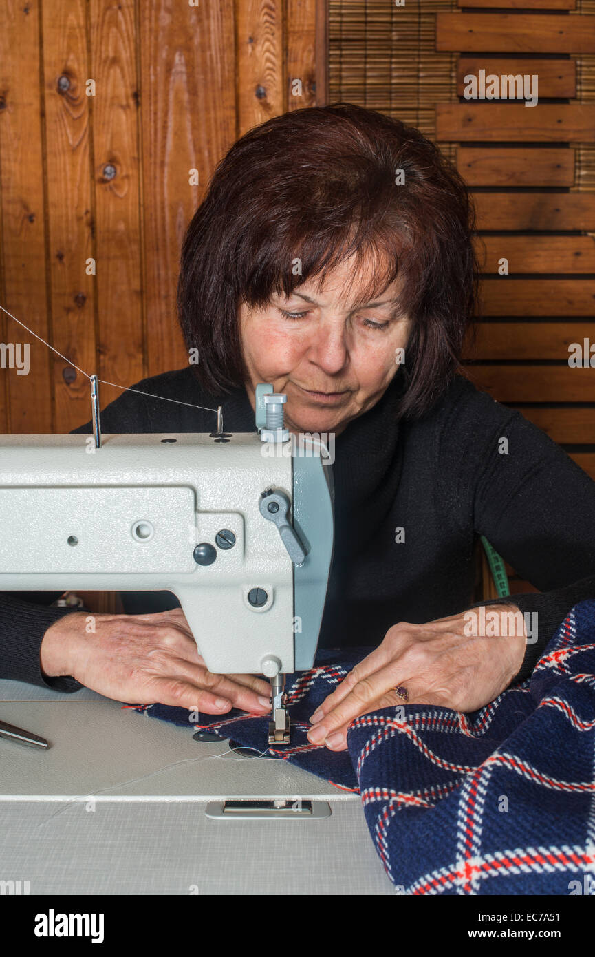 Woman sewing on a sewing machine. Wooden wall Stock Photo Alamy