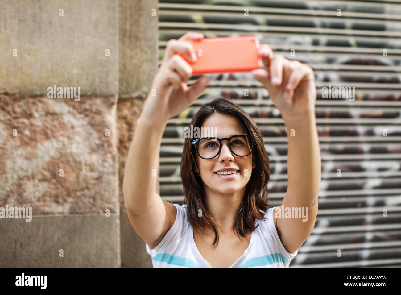 Portrait of smiling young woman taking a selfie with smartphone Stock ...