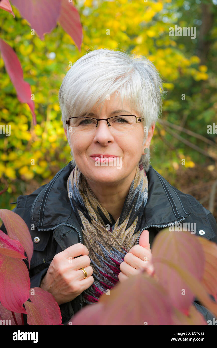 Portrait of smiling senior woman with short grey hair wearing glasses ...