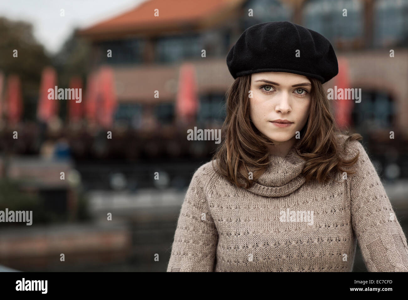 Portrait of serious looking young woman wearing beret and knitted dress ...