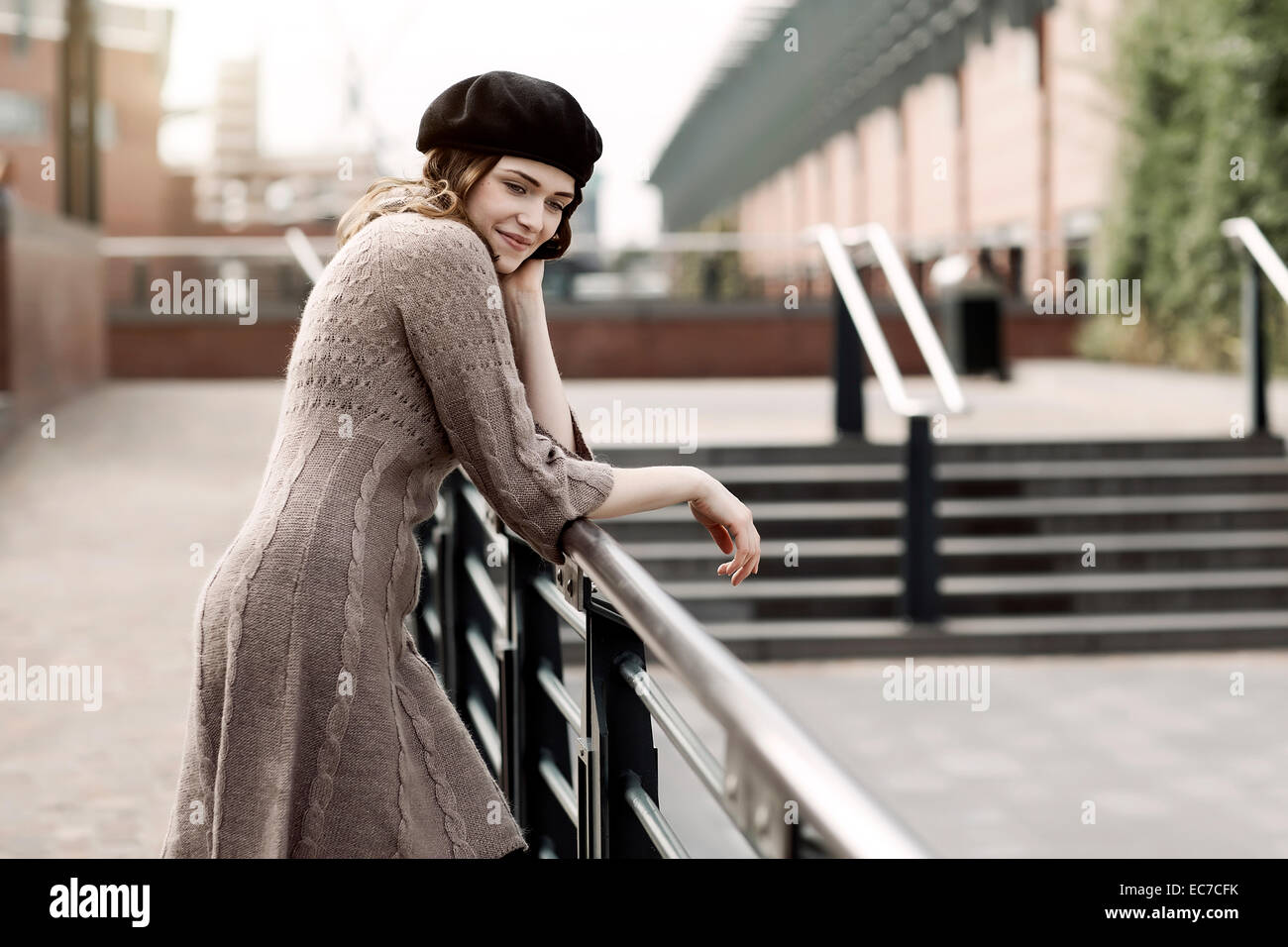 Portrait of young woman wearing beret and knitted dress leaning on a ...