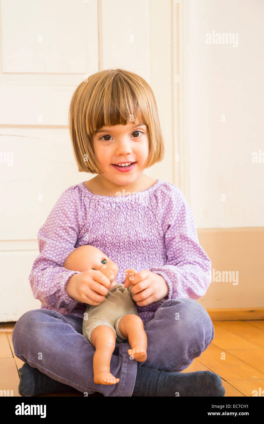 Portrait of smiling little girl playing with doll Stock Photo - Alamy