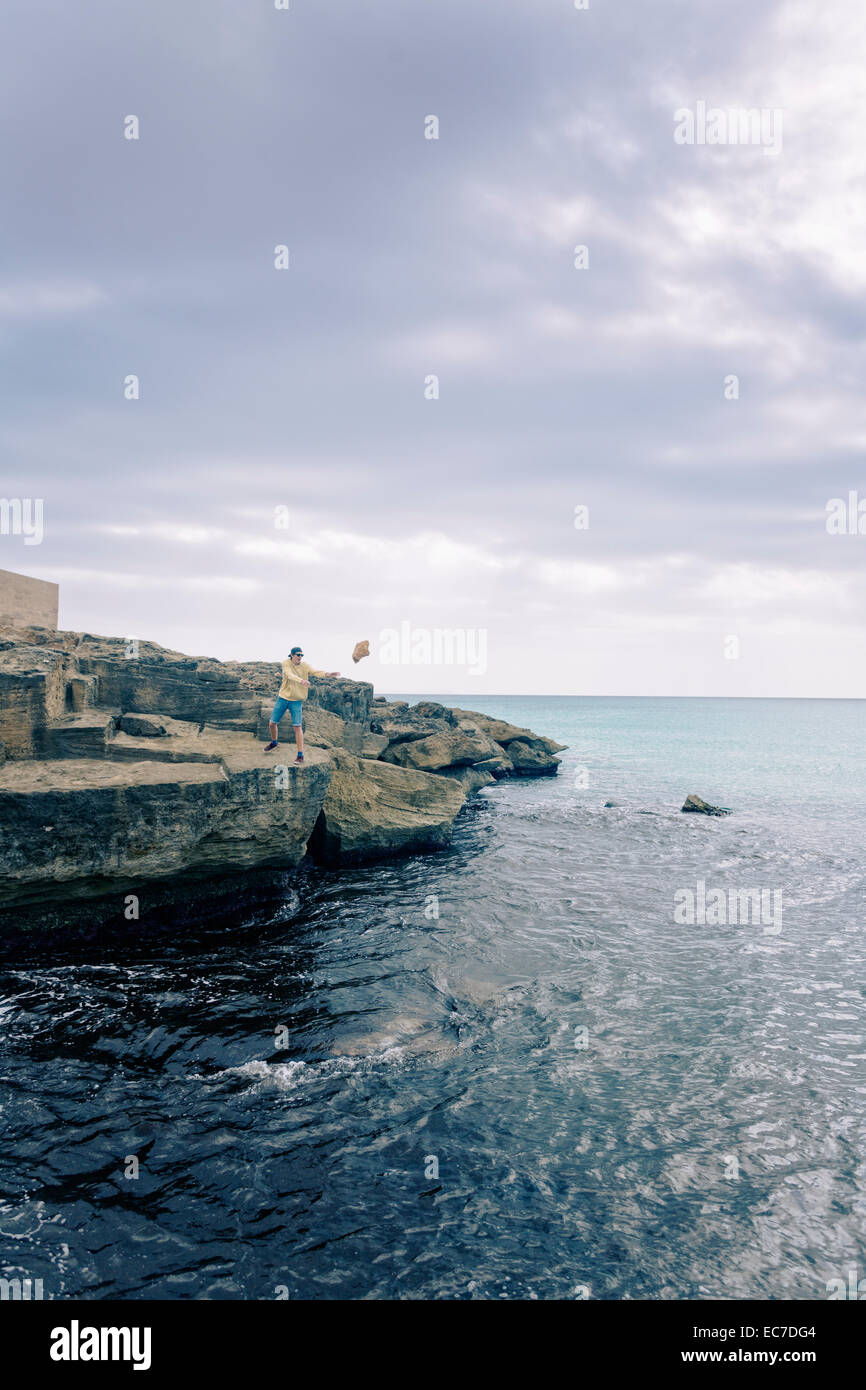 Spain, Balearic Islands, Majorca, one teenage boy throwing a rock into the sea Stock Photo