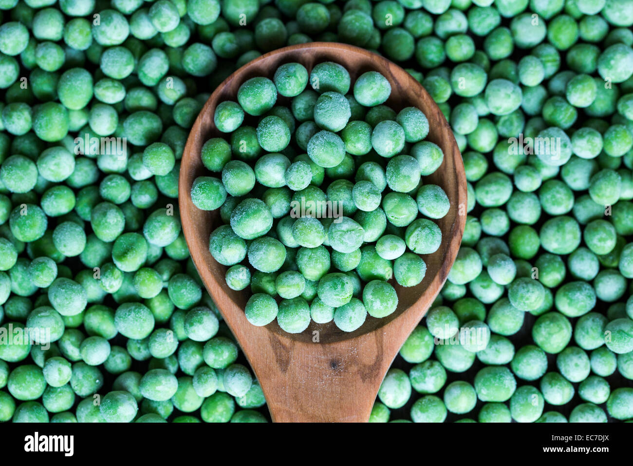Wooden spoon and frozen peas Stock Photo