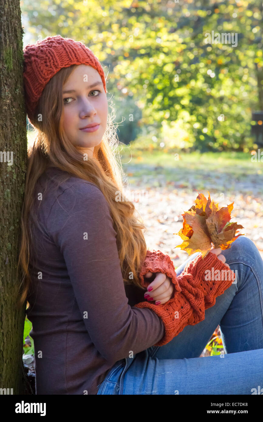 Portrait of teenage girl wearing wool cap and gauntlets leaning at tree Stock Photo Alamy