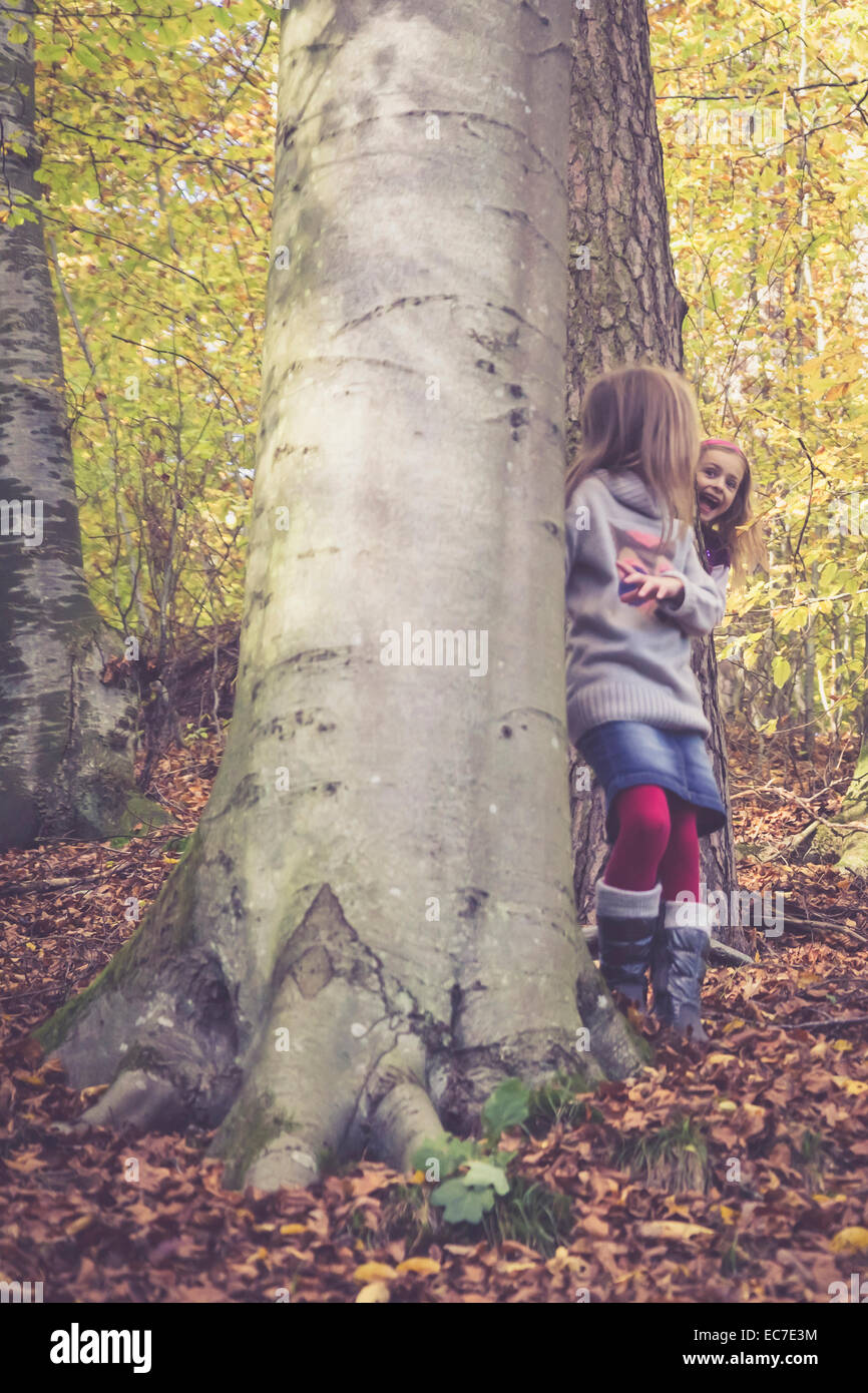 Two little girls playing hide and seek in the wood Stock Photo