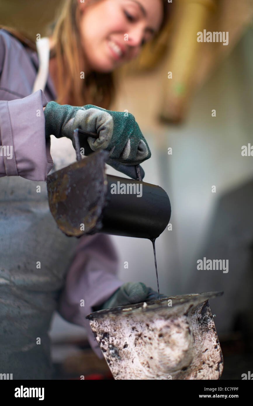 South Africa, Cape Town, Craftswoman pouring wax into casting mold