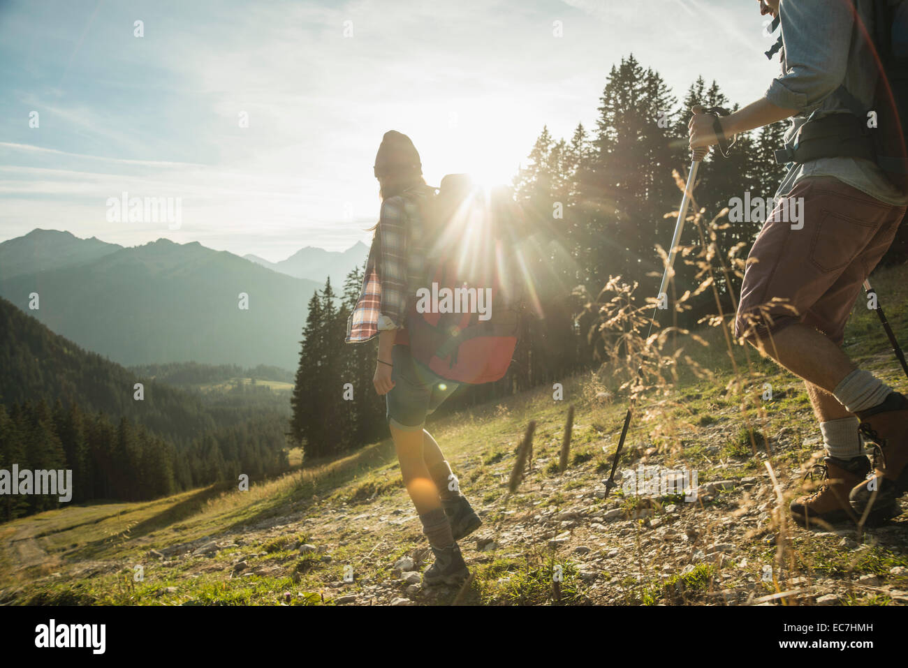 Austria, Tyrol, Tannheimer Tal, young couple hiking in sunlight on alpine meadow Stock Photo