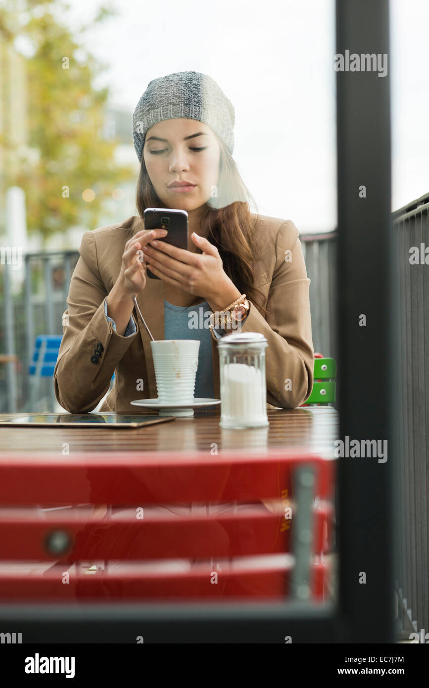 Young woman sitting at sidewalk cafe using smartphone Stock Photo - Alamy