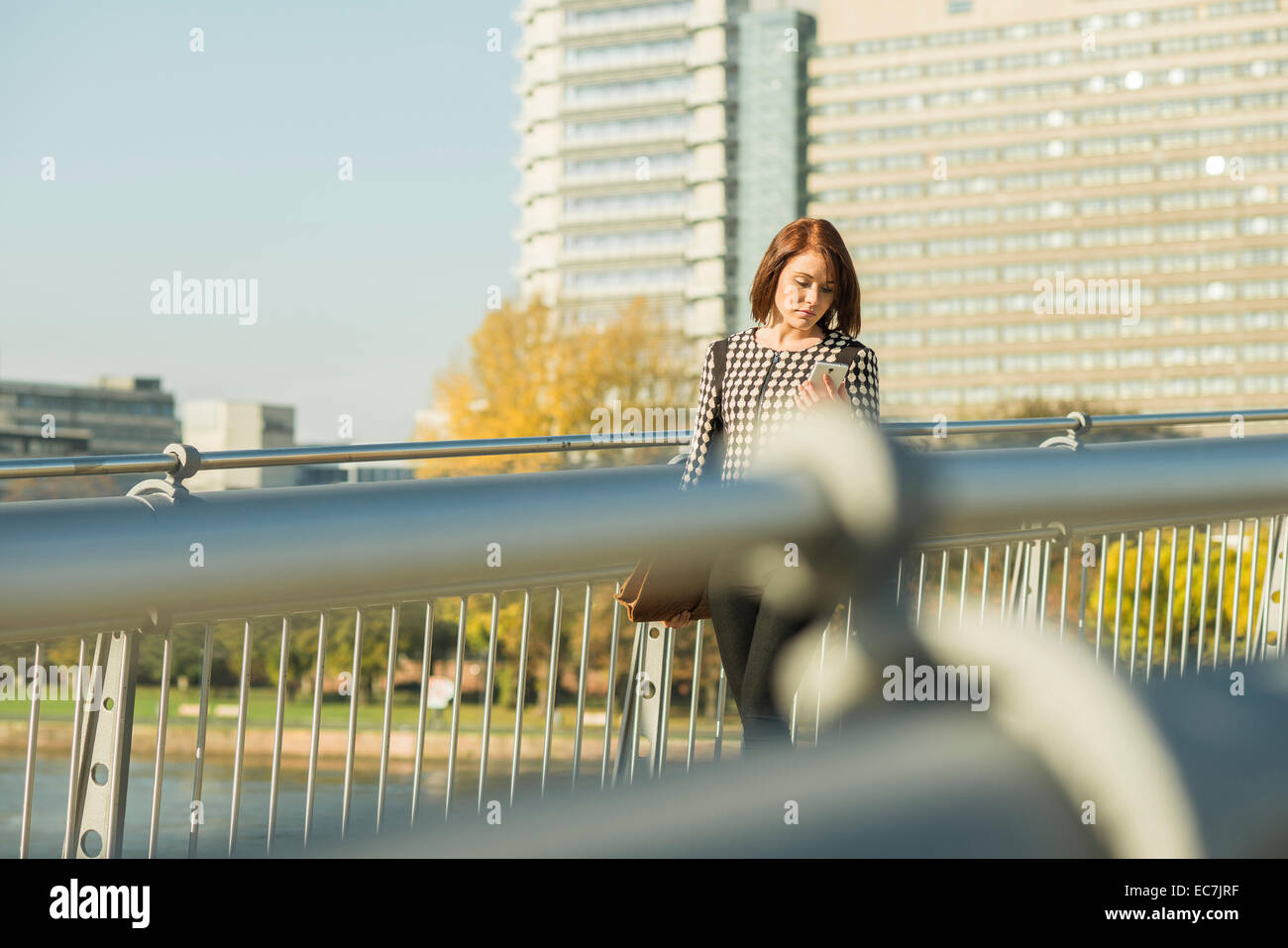 Germany, Frankfurt, young businesswoman with cell phone on bridge Stock Photo