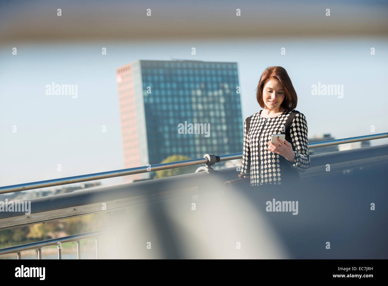 Germany, Frankfurt, young businesswoman on bridge with cell phone Stock Photo