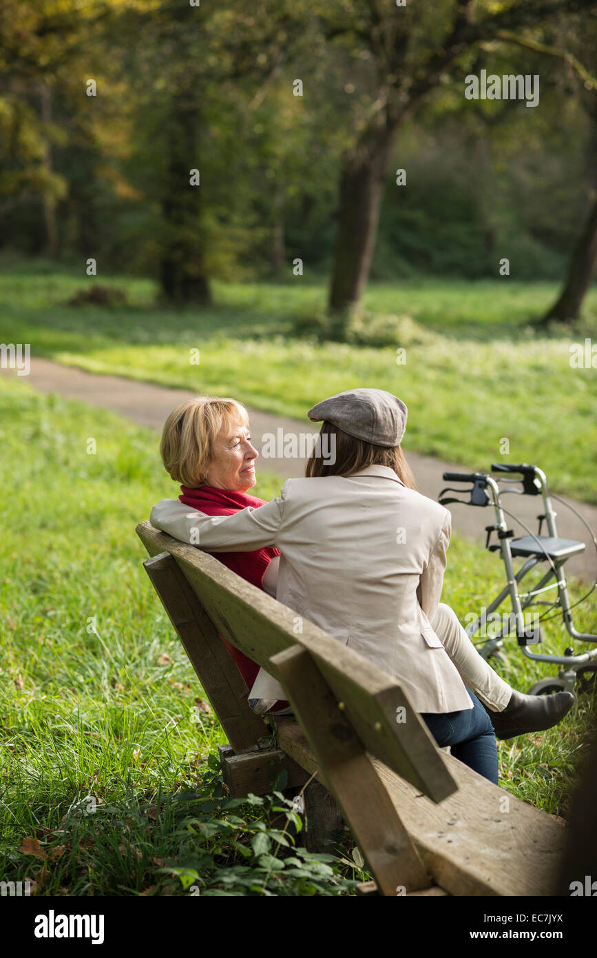 Senior woman and granddaughter sitting on a park bench Stock Photo - Alamy
