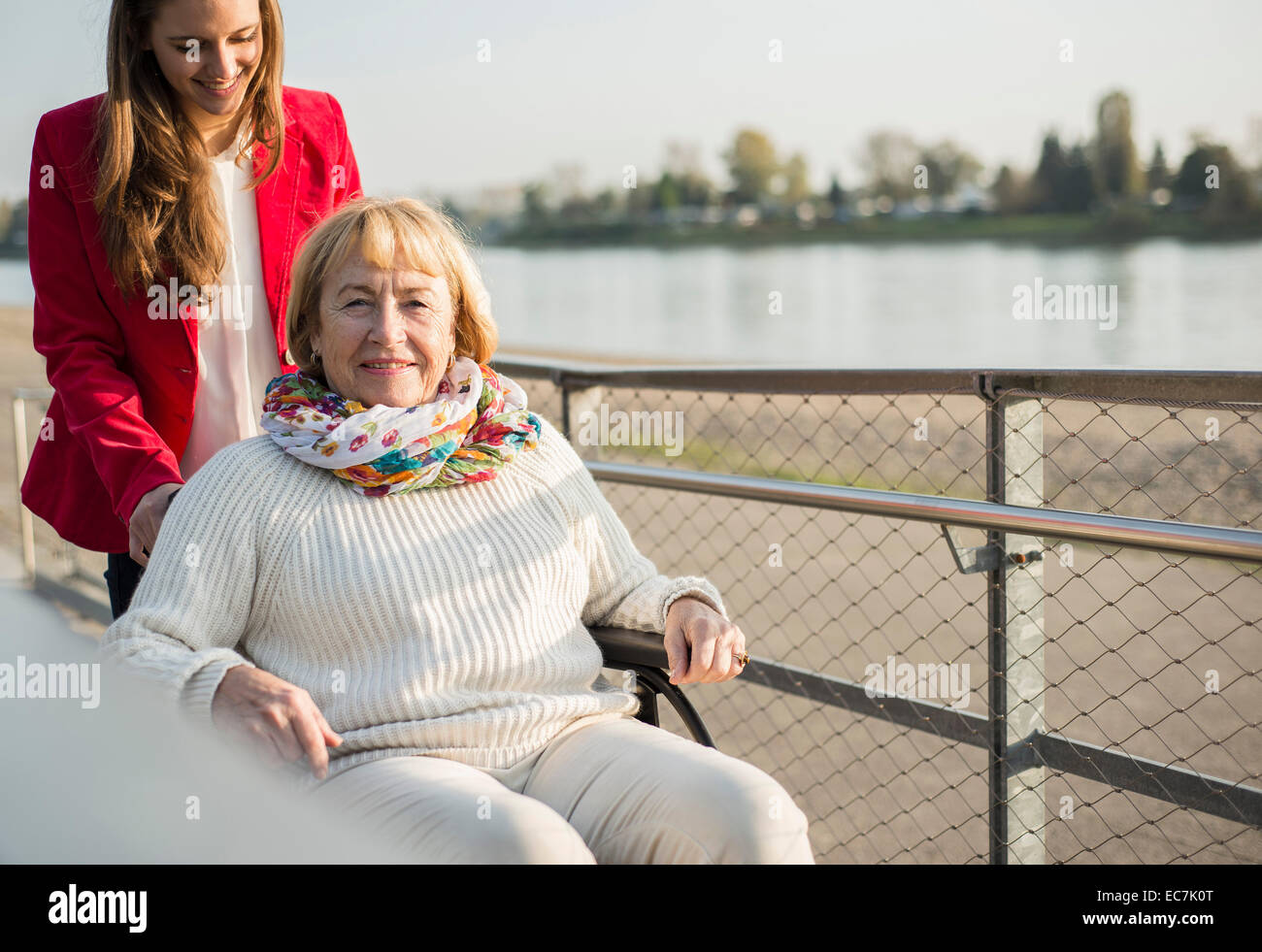 Granddaughter assisting her grandmother sitting in wheelchair Stock Photo