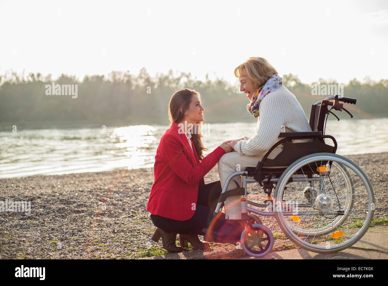 Granddaughter assisting her grandmother sitting in wheelchair Stock Photo