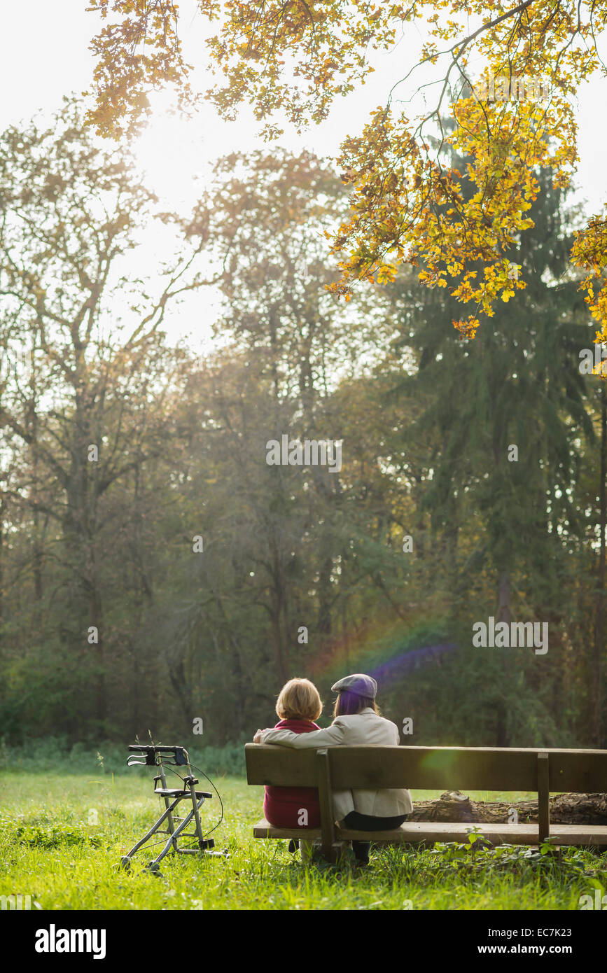 Senior woman and granddaughter sitting on a park bench, back view Stock ...