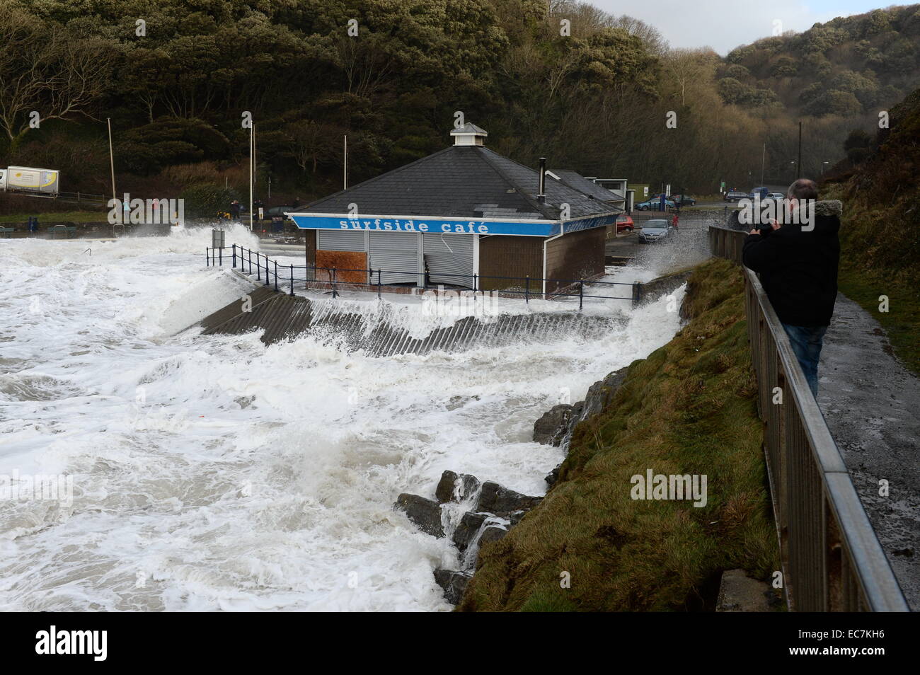 large  waves break over the sea defenses swirling  round the Surfside Cafe  at Caswell Bay  breaking shutters damaging  inside Stock Photo