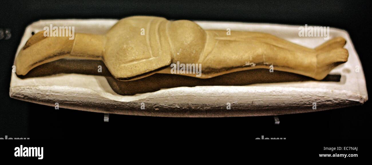 Figurine lying on a palette, modern plaster casts.  Hypothetical reconstruction based on the assumption that some of the palettes may have actually been cradles or beds.  This figurine is portraying a female around six months pregnant. It was found in a grave near Trymalia, Naxos. Stock Photo