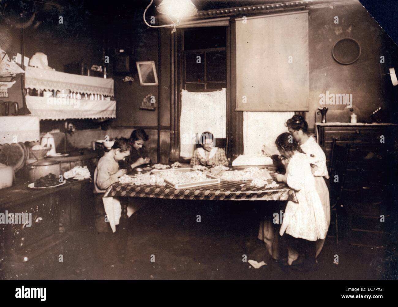 Night scene. 7:30 P.M. January 29; 1912. Making violets; and they often work later. Pollinni family; 5 Carmine St.; N.Y. living in a tenement. Stock Photo