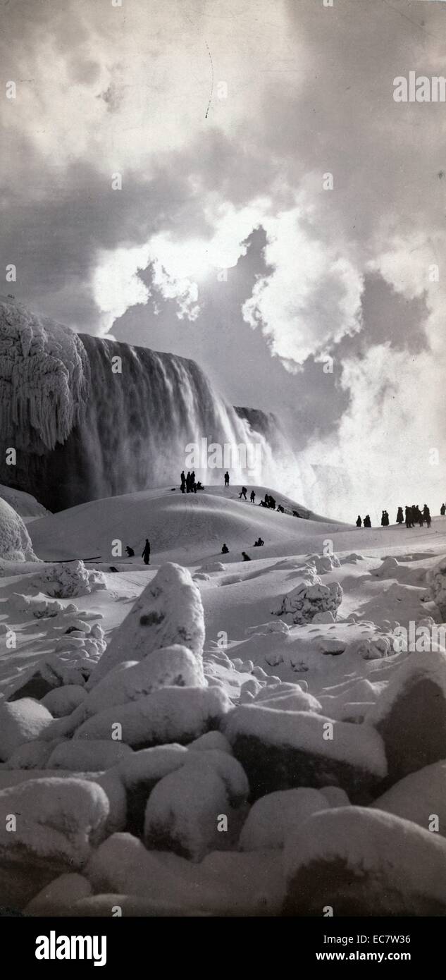 Early photograph of people on snow-covered ice at the base of the frozen Niagara Falls, New York, America - The image was shot around 1883. Stock Photo