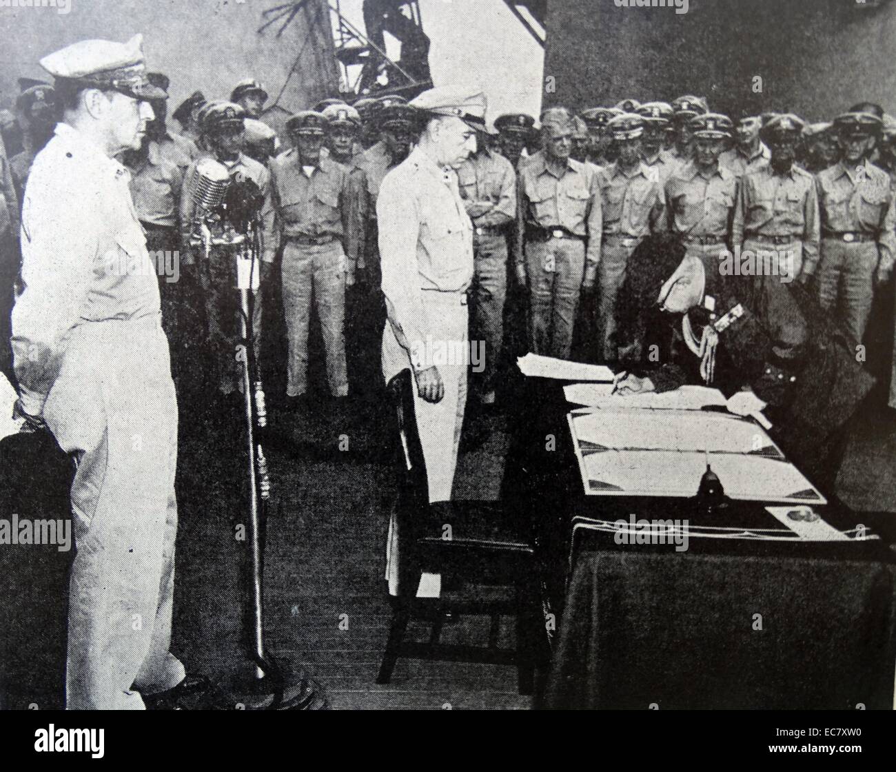 General Douglas MacArthur, Supreme Allied Commander (left) and other Allied military officers look on while Japanese General Yoshijiro Umezu signs surrender document in ceremony aboard the USS Missouri in Tokyo Bay, September 2nd, 1945. Stock Photo