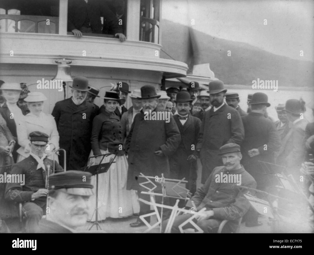 President Benjamin Harrison with James G. Blaine, Secretary of State, Henry Cabot Lodge, and group of other people posed, possibly on the forward deck of the Frenchman's Bay steamer Sappho, with several men of the Bar Harbor Band, Maine 1892 Stock Photo