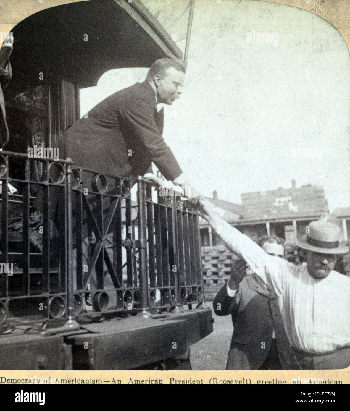Stereograph showing Roosevelt shaking a man's hand from a train.' Democracy of Americanism - an American President (Roosevelt) greeting an American workingman in Tennessee. Theodore Roosevelt (1858 – 1919) was an American politician, author, naturalist, explorer, and historian who served as the 26th President of the United States. Stock Photo