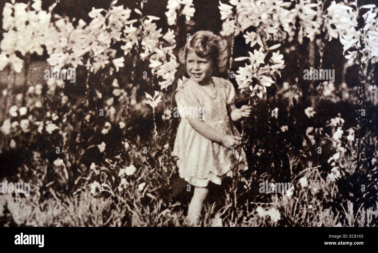 Princess Elizabeth later Queen Elizabeth II, as a child, gathering flowers in a garden. 1930 Stock Photo