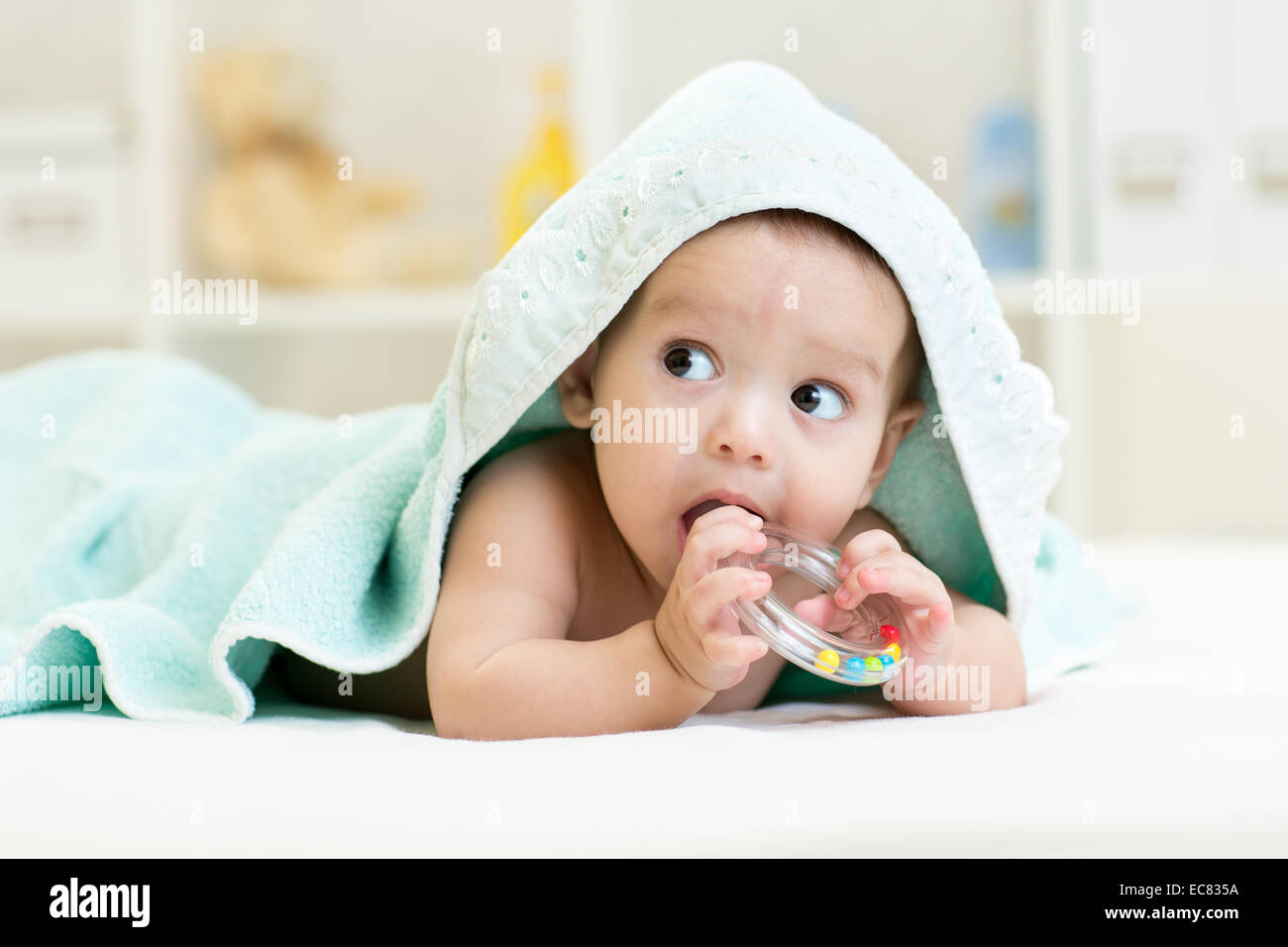 Cute baby boy with teether under towel indoors Stock Photo Alamy