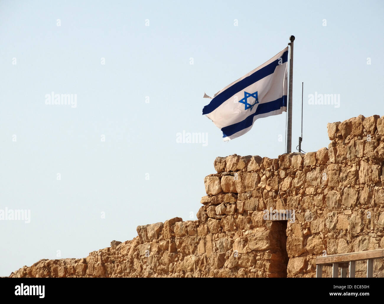 Israeli flag flies above Masada; an ancient fortification in the Southern District of Israel; situated on top of an isolated rock plateau on the edge of the Judean Desert; overlooking the Head Sea. Stock Photo