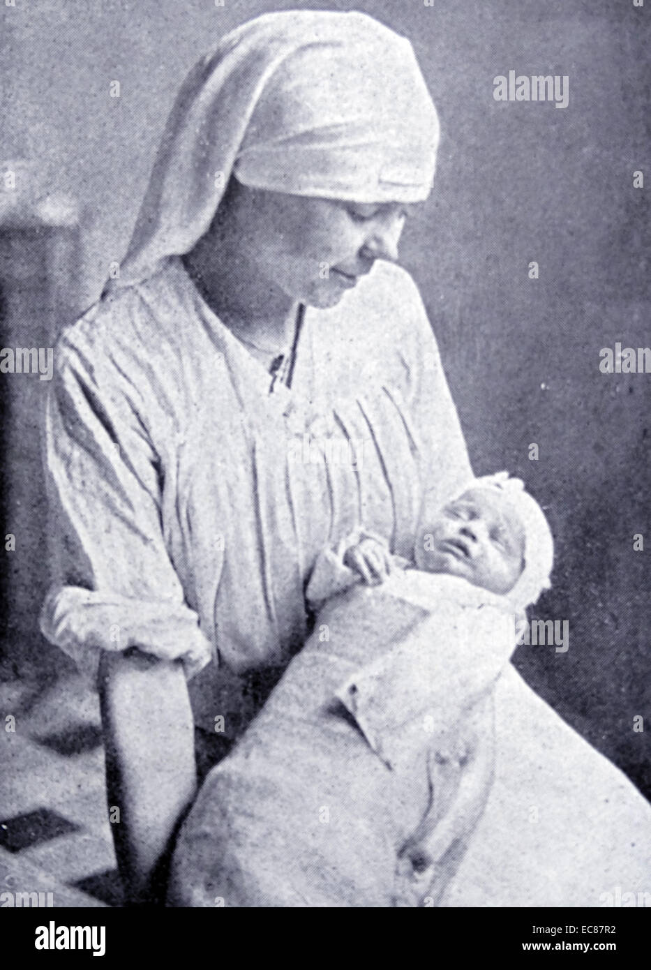 Photograph of a French Nurse attending to an orphan during World War One. Dated 1915 Stock Photo