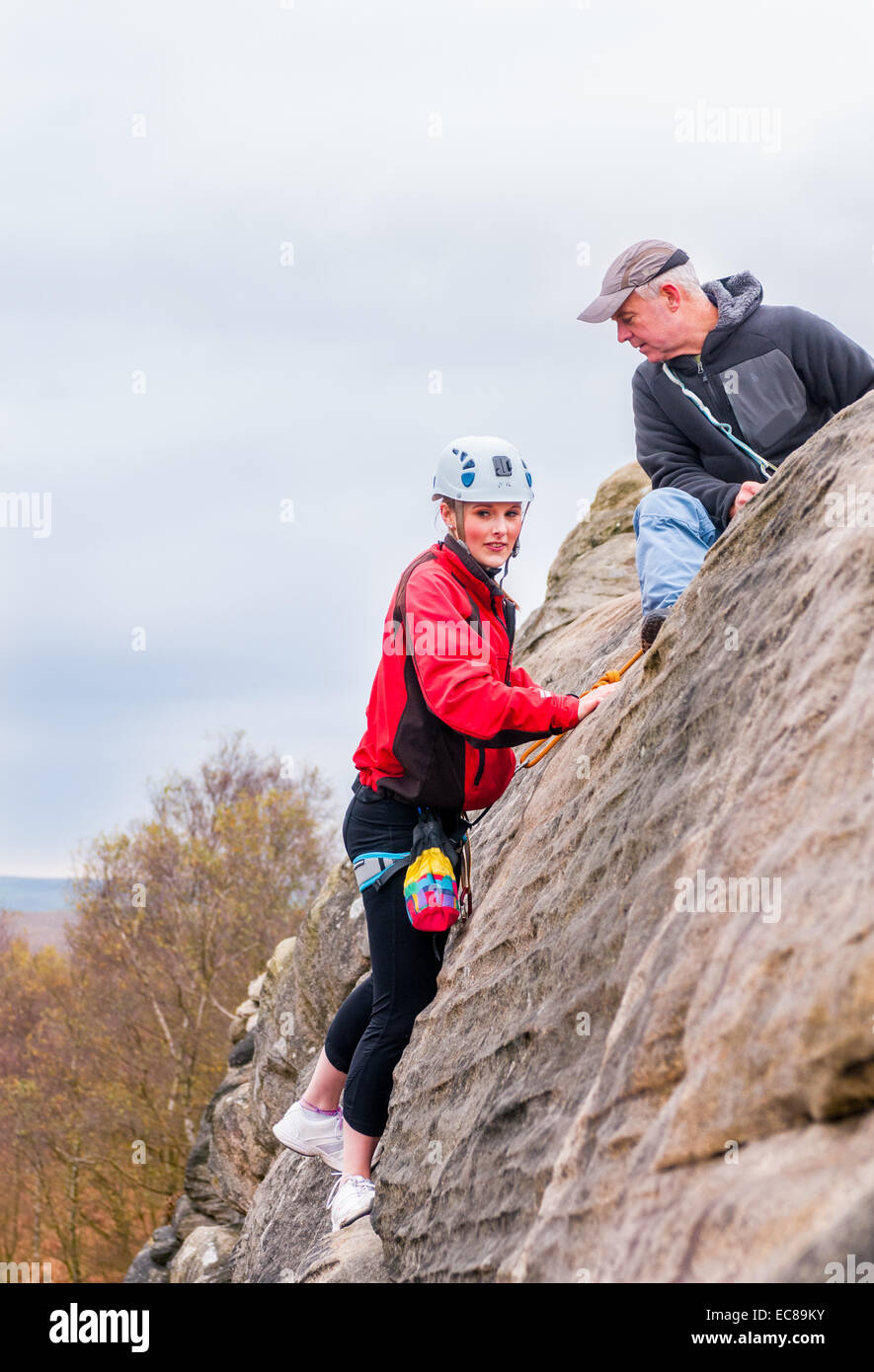 A young teenage girl rock climbing on Birchen Edge in The Peak District of Derbyshire, with an experienced instructor Stock Photo