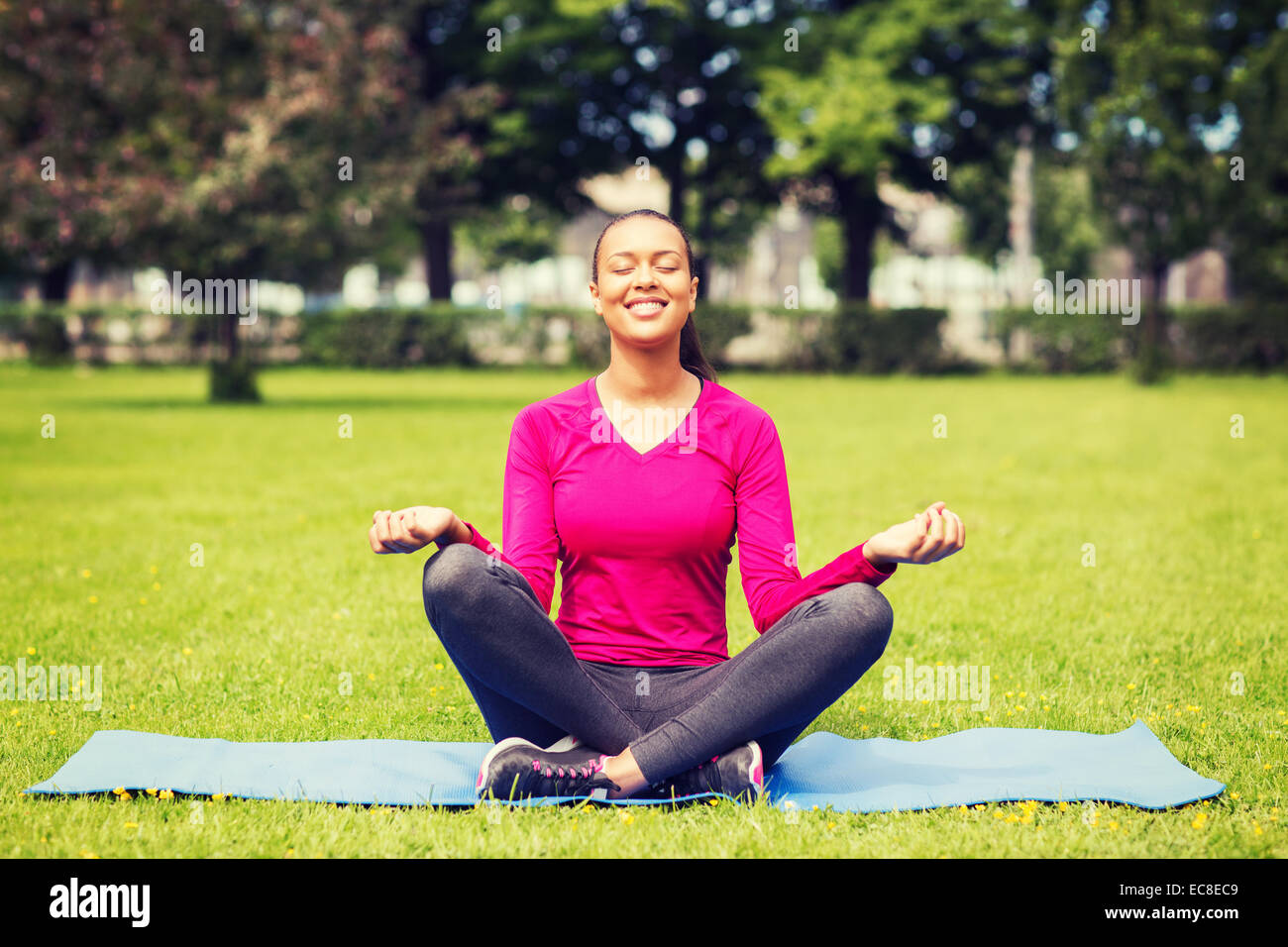 smiling woman meditating on mat outdoors Stock Photo - Alamy