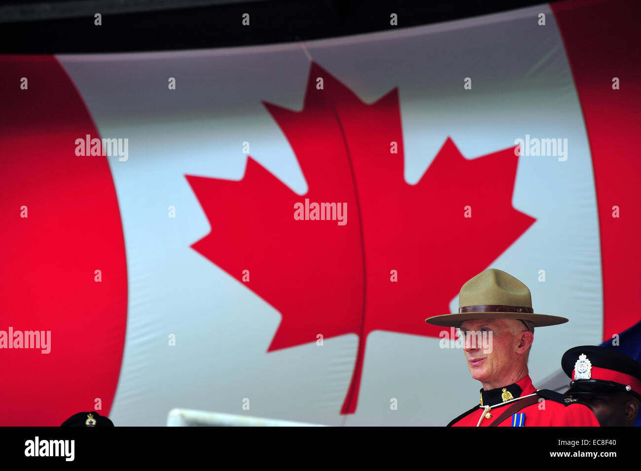 A Mounty stands in front of the Canadian flag during Canada Day celebrations. Stock Photo