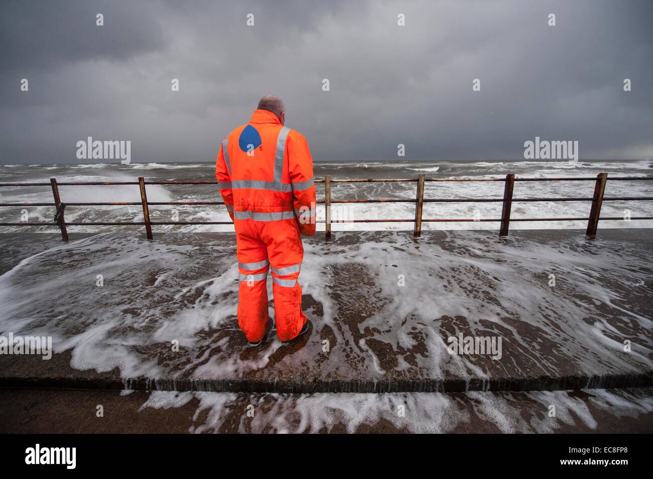 Men dodge the waves as they crash over the promenade wall on December 10, 2014 in Saltcoats, Scotland. Stock Photo