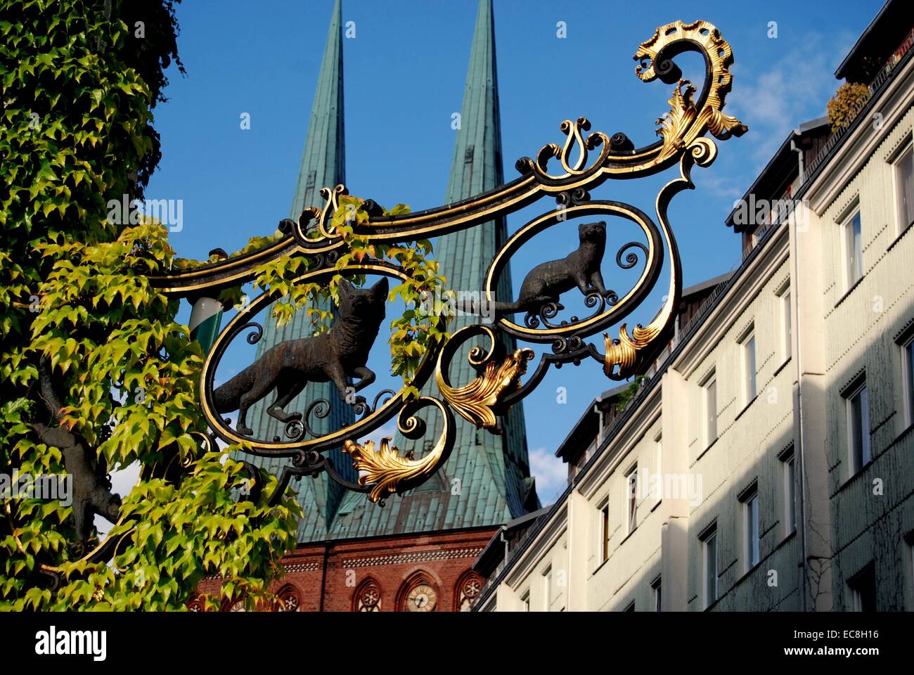 BERLIN, GERMANY:  Gilded wrought-iron shop sign in the Nikolaiviertel with twin spires of the Nikolaikirche in background Stock Photo