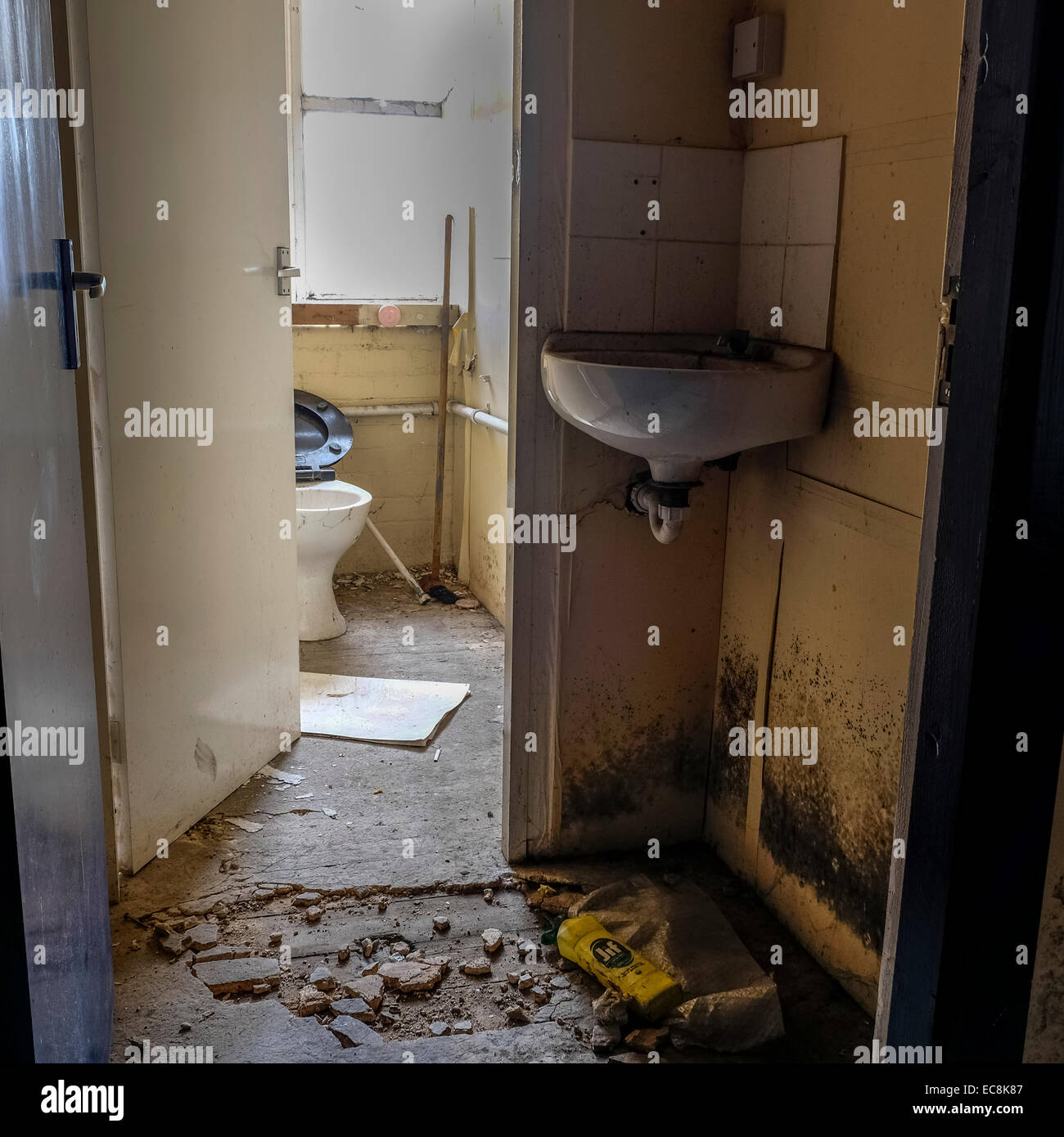 Disused old Lancashire cotton mill in a state of decay with a lot of debris on the floor area with broken toilet in spooky area Stock Photo