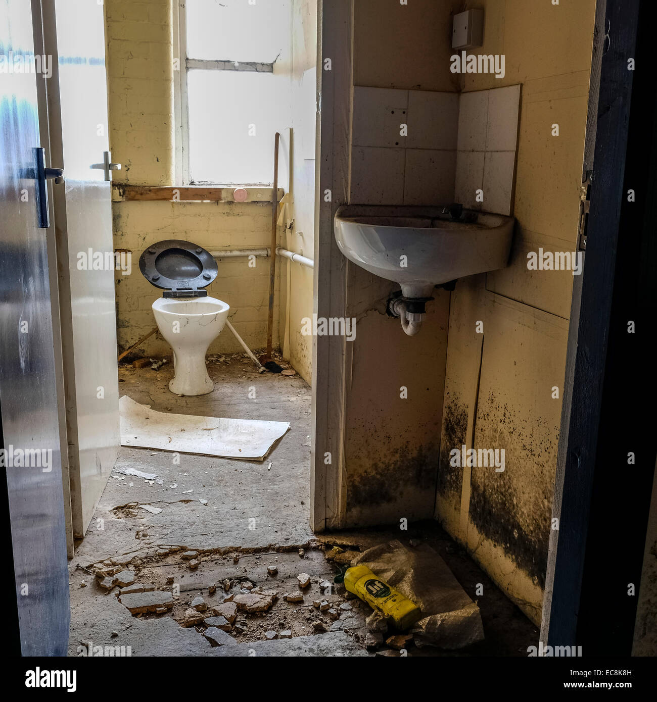 Disused old Lancashire cotton mill in a state of decay with a lot of debris on the floor area with broken toilet in spooky area Stock Photo
