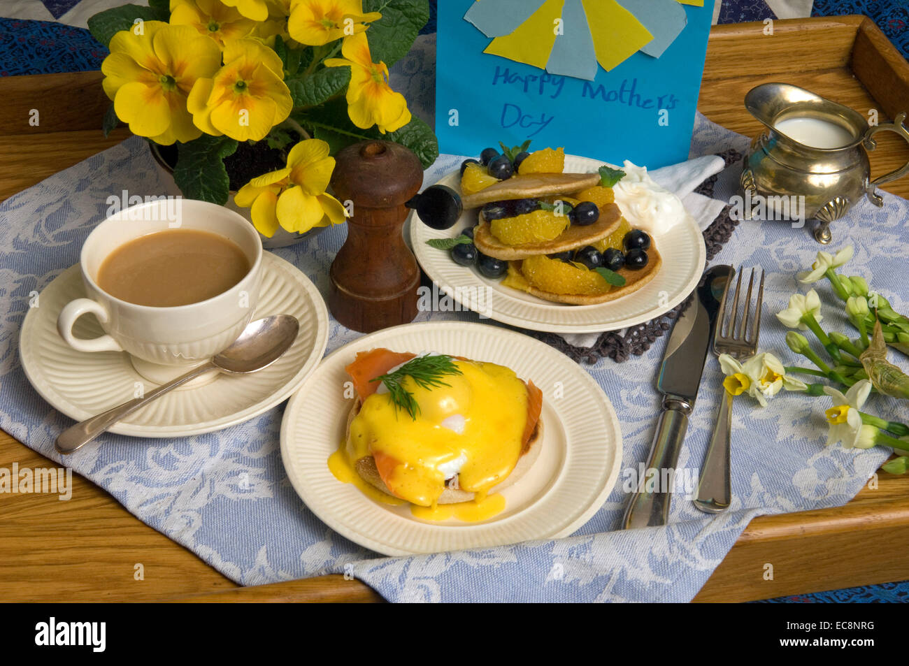 Mother's Day breakfast in bed with eggs benedict and fruit pancakes Stock Photo