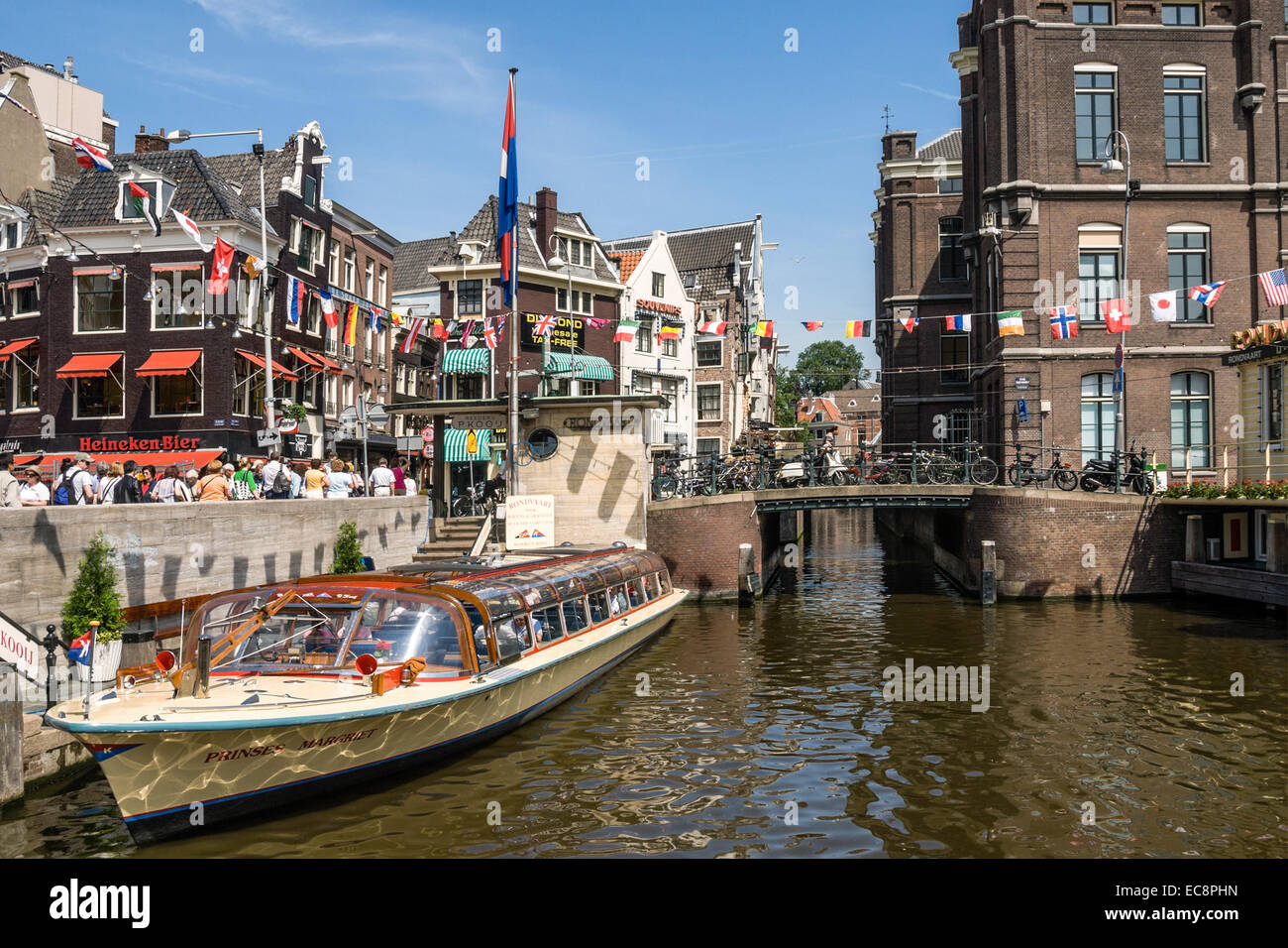 Typical sightseeing boats in a water channel in the city center of Amsterdam, Netherlands. Stock Photo